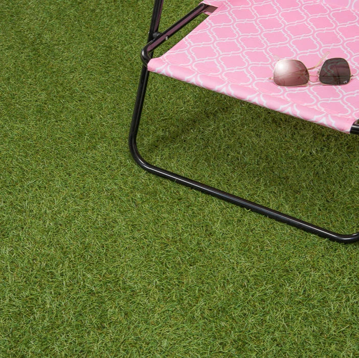 Pink folding table with sunglasses on a grassy surface